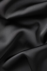 Fototapeta premium Crumpled black silk fabric as background, top view