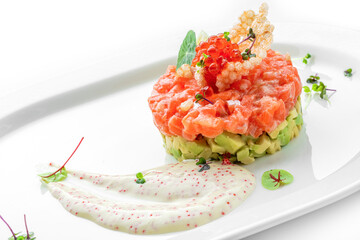 Tartar with salmon fish, avocado and red caviar decorated with microgreens on plate isolated on...