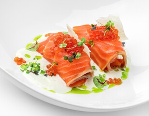 Salmon rolls and red caviar with sauce and greens on plate isolated on white background. Fish and seafood, close up, top view