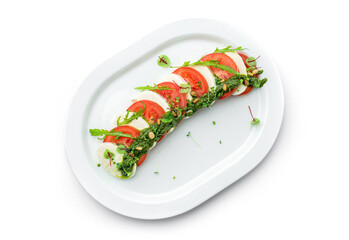Fresh italian Caprese salad with tomatoes, mozzarella cheese and basil in plate isolated on white background, top view, close up