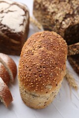 Freshly baked loaves of bread and spikes on light textured table, closeup