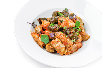 Dolma, cabbage rolls, grape leaves with filling with sour cream in plate isolated on white background. Traditional dishes, top view, close up