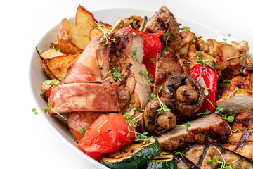 Assorted delicious grilled meat with grilled vegetables on plate isolated on white background. Hot Meat Dishes, top view, close up