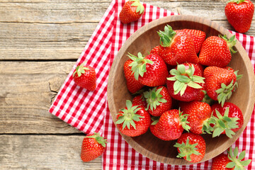 Fresh ripe strawberries in bowl on wooden table, flat lay. Space for text