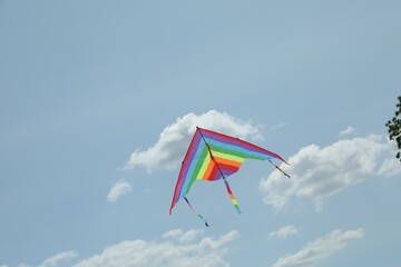 Colorful kite flying in blue sky, low angle view. Space for text
