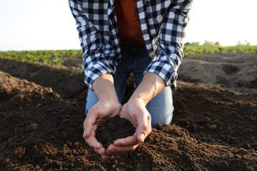 Man holding pile of soil in field, closeup
