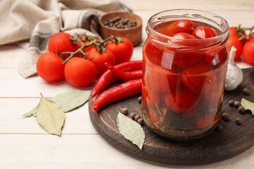 Tasty pickled tomatoes in jar and ingredients on wooden table, closeup