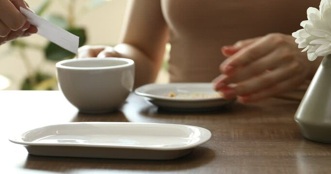 Waitress giving receipt to client indoors, closeup. Woman putting tips onto plate at wooden table in cafe