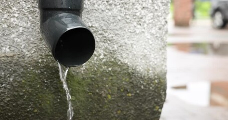 Water flowing from drain pipe outdoors, closeup