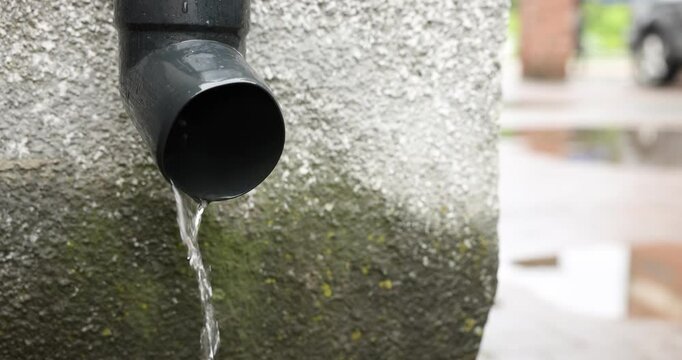 Water flowing from drain pipe outdoors, closeup
