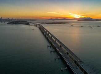 Aerial view of the San Francisco-Oakland Bay Bridge in California, USA, at sunset. Cars travel across the bridge, connecting San Francisco to Oakland.