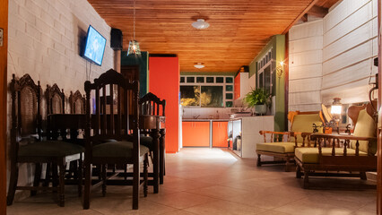A cozy indoor space featuring a rustic dining table, cushioned wooden chairs, and a small kitchen...