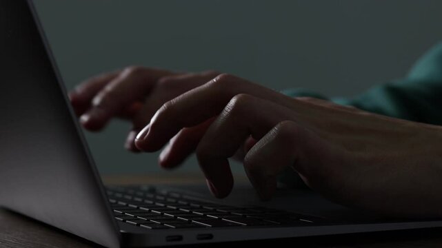Man typing on laptop at table, closeup