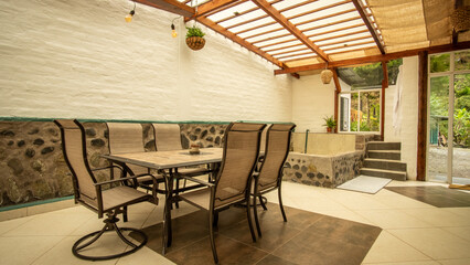 Rustic interior with stone hot tub, dining table, chairs, glass doors, and natural light, ideal for spa retreats.