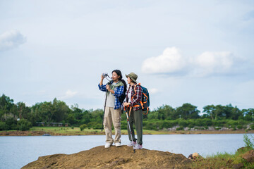 Two young Asian female hikers enjoying an outdoor adventure in nature. Exploring scenic trails,...