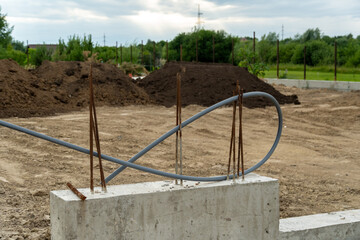 Workers are laying the foundation at a construction site, where rebar and electrical conduit are...