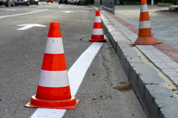 Traffic cones line the street, indicating ongoing construction work. Vehicles are rerouted while...
