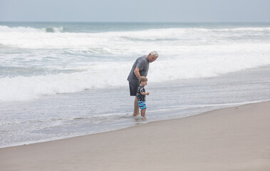 Senior Grandfather and Grandson Walking Together on the Ocean Shore
