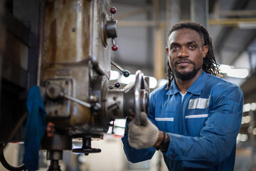 African american factory male worker. Engineer man worker in plant production drilling at robotic machine in smart factory wearing yellow hard hat safety first at robot mechanic factory.