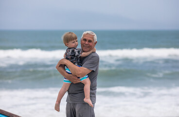Senior Grandfather and Grandson Walking Together on the Ocean Shore