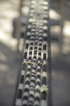 Hilos en telar tradicional con guarda en negro y crema, entre luces y sombras suaves