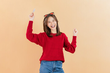 Cheerful beautiful Asian woman holding credit card isolated on beige color background.