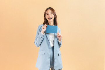 Happy Asian businesswoman stands with holding blue envelope, against a beige background.
