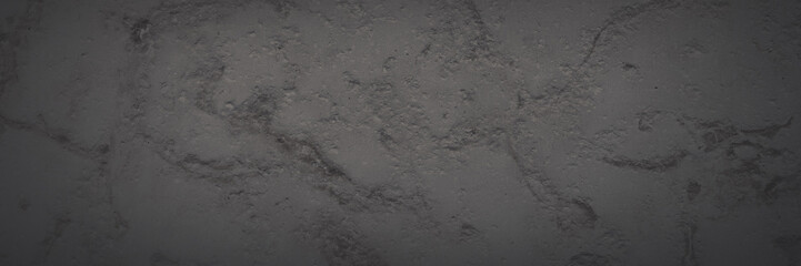 Dark wide panoramic background. Natural rock with patterns on the surface. Dolomite texture. Solid stone background for design. Shaded faded texture with vignette.