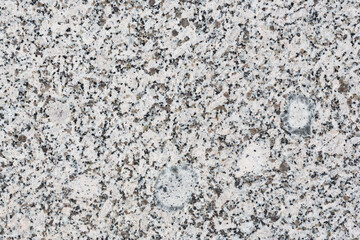 Granite texture. Natural gray granite with a grainy pattern. Stone background. Solid rough surface of rock. Durable construction and decoration material. Close-up.