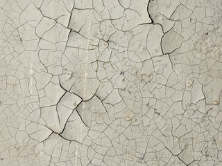Peeling paint on the wall. Old concrete wall with cracked flaking paint. Weathered rough painted surface with patterns of cracks and peeling. Grunge texture for background and design.