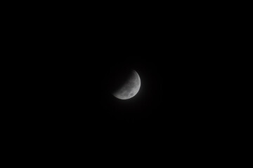 full moon during a partial phase of an eclipse with mist and black background