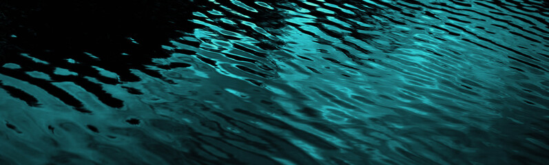 Black dark blue green teal water. Night. Ripples reflection light moonlight. Little waves. Gradient. Abstract. Contrast. Sea surface. Background with space for design. Wide banner. Panoramic.