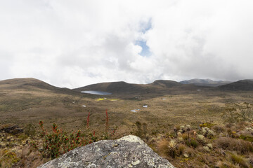 paramo ecosystem landscape viewed from a big stone in colombia with cloudy sky at background