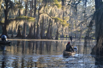 A man is kayaking on Caddo Lake in Texas at sunrise