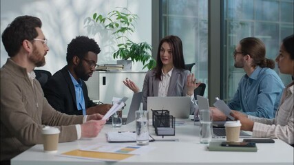 Multicultural Caucasian Indian group businesswomen businessmen women men business teamwork office coworkers females males discuss project together talking paperwork documents cooperate diverse people - Powered by Adobe