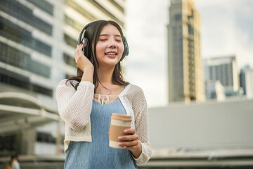 Young asian woman wearing headphones and enjoying music on the urban city, Female listening to music on the town, phone and woman dancing, streaming and enjoying radio, audio or sound podcast