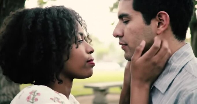 Cinematic close-up of a loving interracial couple sharing an intimate and tender moment outdoors.