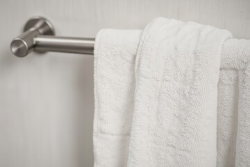 White towel hanging on a chrome towel rack.