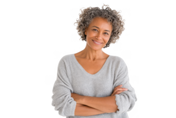 A smiling older woman with curly hair stands confidently with her arms crossed. wearing a cozy gray sweater against a plain background. exuding warmth and approachability. ideal for lifestyle imagery