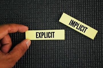 Paper with the words explicit and implicit. motivational words positive and negative. contrasting...