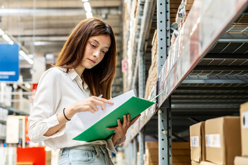 Focused on her task, a young woman holding clipboard meticulously updates inventory records while surrounded by shelves filled with various products in a vibrant warehouse setting