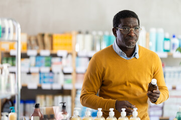 African American man buyer select antiallergic syrup, reads composition, finds out information...