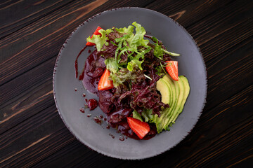 Warm liver salad with avocado, strawberry, and greens