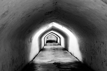 A long, mysterious arched tunnel in black and white, showcasing deep perspective and architectural...