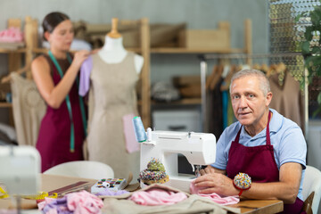 Girl tailor connects parts of dress on mannequin. Craftsman attaches front part of dress to back...
