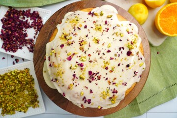 Baking a Persian Love Cake with rose petals, pistachios, citrus and exotic spices like cardamom.  Dessert cake topped with a glaze and sprinkled with rose petals and crushed pistachios.  Love cake.
