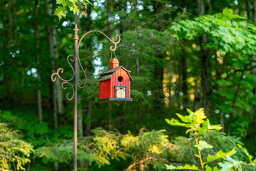 Red birdhouse suspended on a garden hook