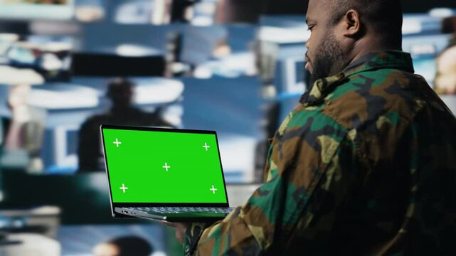 African american trooper holding laptop with copy space screen in a control tower, using modern digital tools and satellite imagery to ensure a successful national defense matter. Camera B.