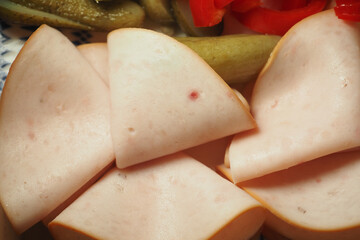 Slices of deli meat with pickles and red peppers on plate
