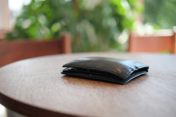 Black wallet resting on wooden table in bright cafe